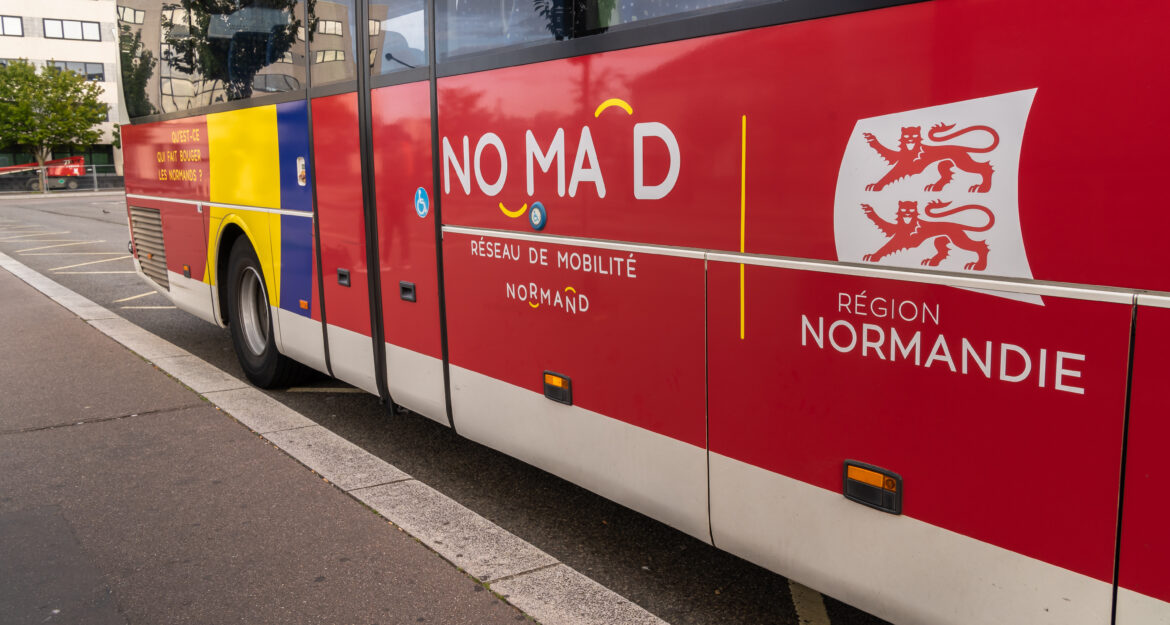 Autocar rouge du réseau de mobilité Nomad en Normandie, stationné sur la voie publique