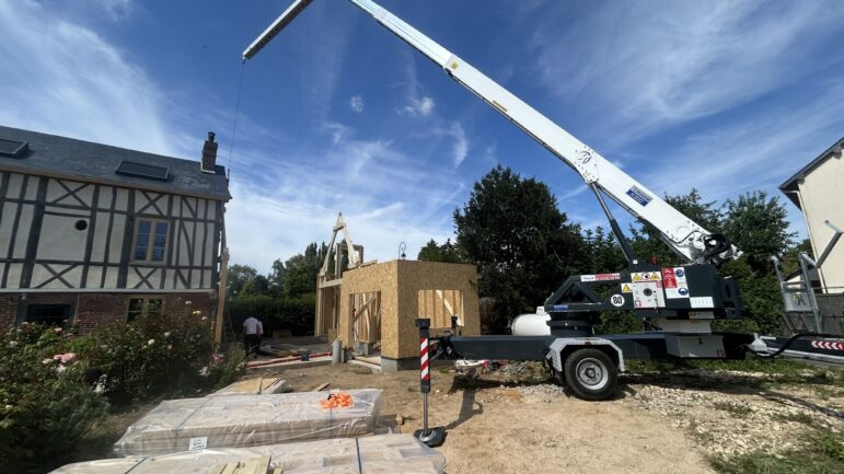 Utilisation d'une grue K300E pour la levée d'une ossature bois par les équipes de BM Couverture.