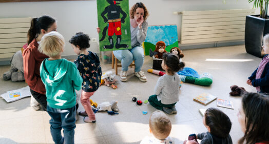 Une animatrice du Relais Petite Enfance présente un dessin à un groupe d'enfants et de parents lors d'un atelier, territoire de Lyons Andelle.