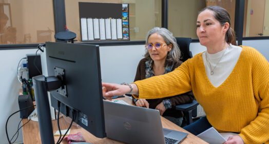 Deux agentes du service assainissement collectif prises en photo au travail. Elles échangent sur un projet, devant le même écran d'ordinateur.