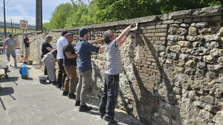 Bénévoles rejointoyant le mur d'enceinte en silex et brique du château de Pont-Saint-Pierre
